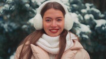 Close up portrait young woman with fur earmuffs winter day outdoor. video