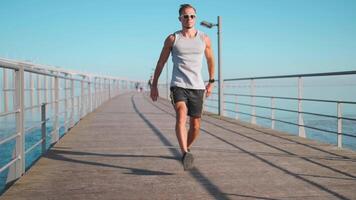 masculino corredor corrida em ponte ensolarado dia. atleta fazendo cardio treinamento. video