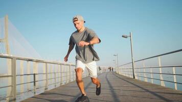 masculino corredor corrida em ponte ensolarado dia. atleta fazendo cardio treinamento. video