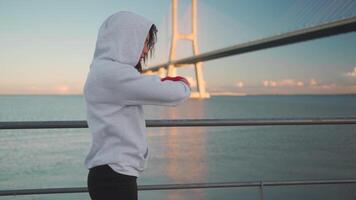 Woman shadow taking fighting pose with her hands wrapped in red boxing tapes with city seascape background. video