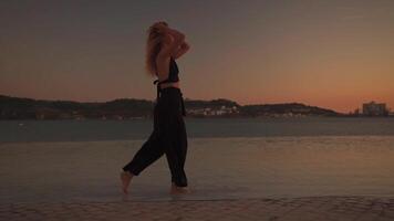 femmina ballerino danza nel acqua a tramonto luce. video