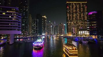 uae, dubai - förenad arab emirates 01 april 2024 nattetid kryssning i dubai marina, lysande dhow båtar segla genom de dubai marina flankerad förbi upplyst höghus på natt. video