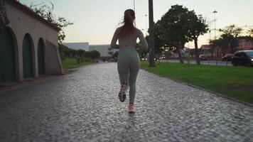 Young adult fitness woman jogging by embankment area coastal city in beautiful sunny day. video