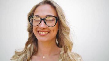 portrait de une femme avec des lunettes souriant vers le caméra video