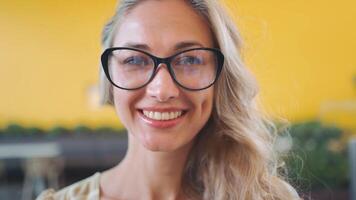 retrato de un mujer con lentes sonriente hacia el cámara video