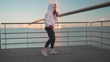 Woman shadow boxing with her hands wrapped in red boxing tapes in park with punching box. video