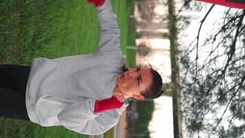 Woman shadow boxing with her hands wrapped in red boxing tapes in park with punching box. video
