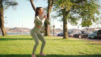 Young adult fitness woman exercising outdoor on green grass. video