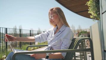 a woman in glasses sitting while working on her laptop video