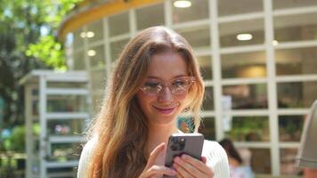 un mujer en lentes utilizando su teléfono video