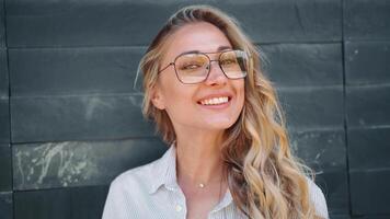 portrait de une femme avec des lunettes souriant vers le caméra video