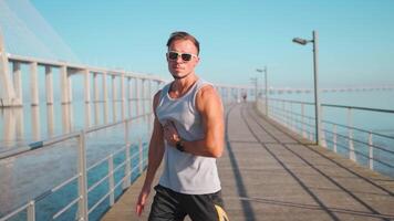 masculino persona que practica jogging corriendo en puente soleado día. atleta haciendo cardio capacitación. video