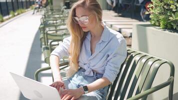 une femme dans des lunettes séance tandis que travail sur sa portable video