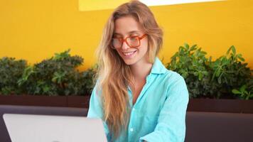 a woman in glasses sitting while working on her laptop video