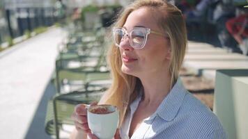 ein Frau ist Sitzung auf ein Bank mit ein Tasse von Kaffee video