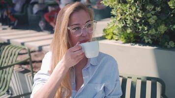 a woman is sitting on a bench with a cup of coffee video