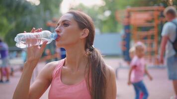 une femme est en buvant l'eau de une bouteille video