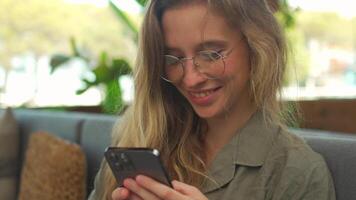 un mujer en lentes utilizando su teléfono video