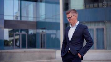 un hombre en un traje y lentes es mirando a su teléfono video