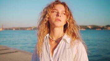 Woman wear white shirt with curly hair standing near the water video