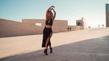 Fashion woman with curly hair dressed black dancing outside looking at camera. video