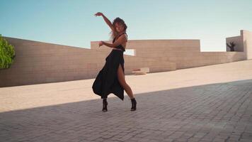 moda mulher com encaracolado cabelo vestido Preto dançando lado de fora olhando às Câmera. video