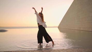 Female dancer dancing in water at sunset light. video