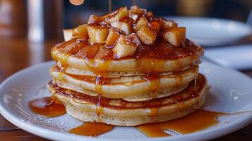 A stack of pancakes with apples on top and powdered sugar on the plate. The pancakes are piled high and look delicious photo