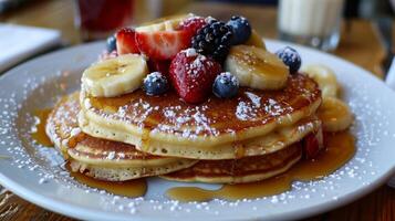 A stack of pancakes with strawberries and blueberries on top photo