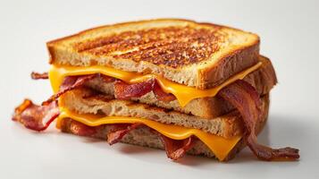 A sandwich with bacon and cheese on it. The sandwich is cut in half and is sitting on a white table photo