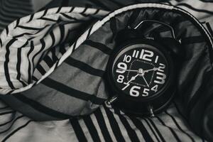 Deadline and Time management concept. Black retro alarm clock on bed. time to wake up for the morning routine photo