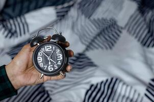 Time management concept. Man hands holding Black retro alarm clock. Time to wake up for the morning routine photo