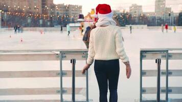 ung leende kvinna is skridskoåkning utanför på is rink. video