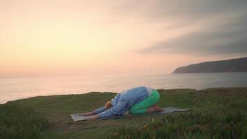 senior kvinna praktiserande yoga övning på de strand. video