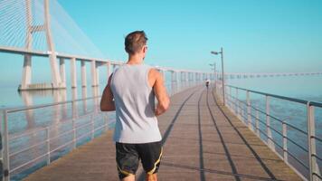 Male jogger running on bridge sunny day. Athlete doing cardio training. video