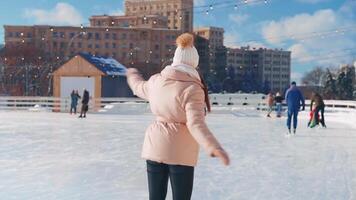 ung leende kvinna is skridskoåkning inuti på is rink. video