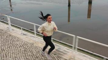 Woman jogging alone by embankment area city in beautiful sunny autumn morning. video