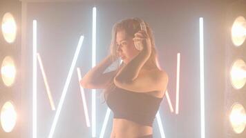 artístico joven mujer auriculares disfrutar música bailando en retroiluminado niebla fumar adentro. video