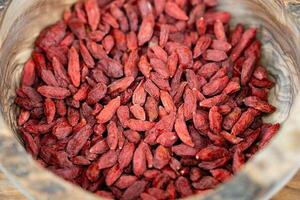 dried goji berries on olive wood photo