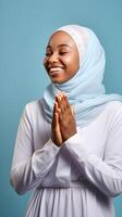 AI generated African woman wearing scarf is praying and smiling on blue background photo