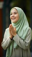 AI generated Portrait of a pretty muslim woman wearing green scarf praying and smiling outdoor. religious, peace and happiness concept photo