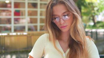 a beautiful young woman in glasses sitting on a bench reading a book video