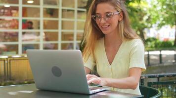 ein Frau im Brille Sitzung beim ein Tabelle mit ein Laptop. Fernbedienung Arbeiten Konzept video