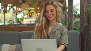 een vrouw in bril zittend Bij een tafel met een laptop. afgelegen werken concept video