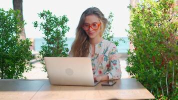 a woman in glasses sitting at a table with a laptop. remote working concept video