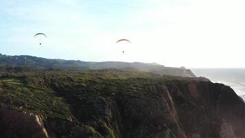 Extreme paraglider flying in clear blue skies, toward cinematic teal ocean. video