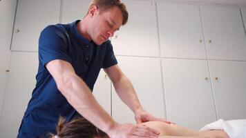 professionell terapeutisk massage i de klinik. massör massage tillbaka och axlar kvinna patient vem lögner på massage tabell i massage rum. video