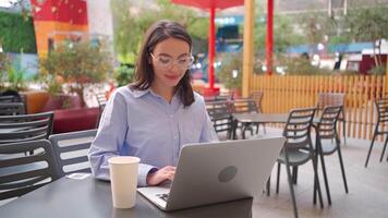 een vrouw in bril zittend Bij een tafel met een laptop video