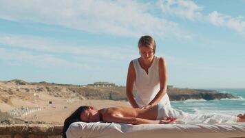Frau genießen Fachmann Spa Hand Massage Lügen auf Besondere Tabelle auf Strand während Urlaub. Massage Therapeut geben entspannend Massage Kunden Waffen und Schultern video