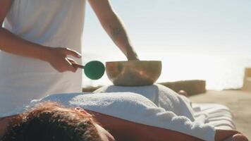 mujer disfrutando profesional spa mano masaje acostado en especial mesa en playa durante vacaciones. masaje terapeuta dando relajante masaje clientela brazos y espalda video